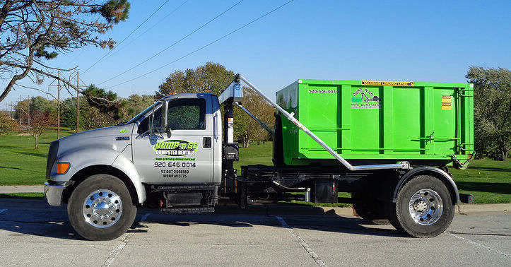 A truck hauling a small dumpster.